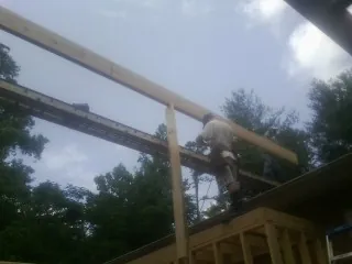 Carpenter setting a ridge beam over a new addition frame — Ice Dam Removal by Roofing Brothers in Romney