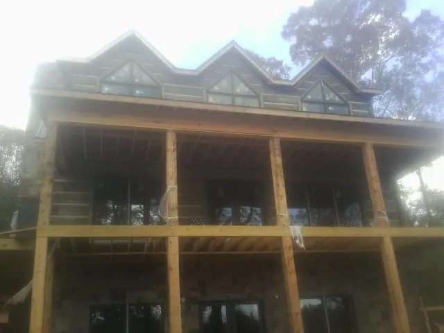 Dormers and porch framing on a large log home under construction — Roof Coating work by our crew in Romney