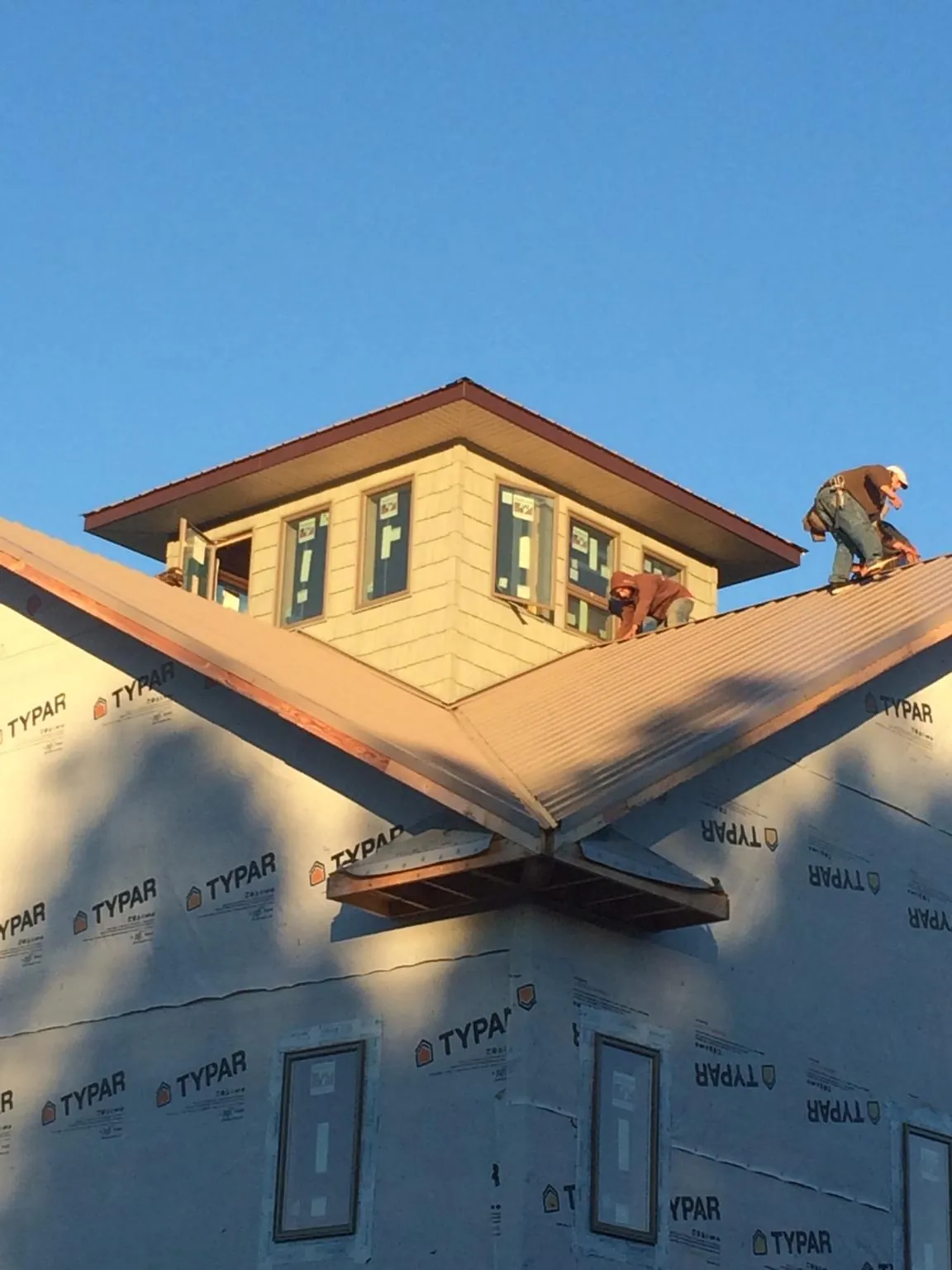 Roofers working around a rooftop cupola on a new metal roof at sunset — Roof Waterproofing in Romney by Roofing Brothers
